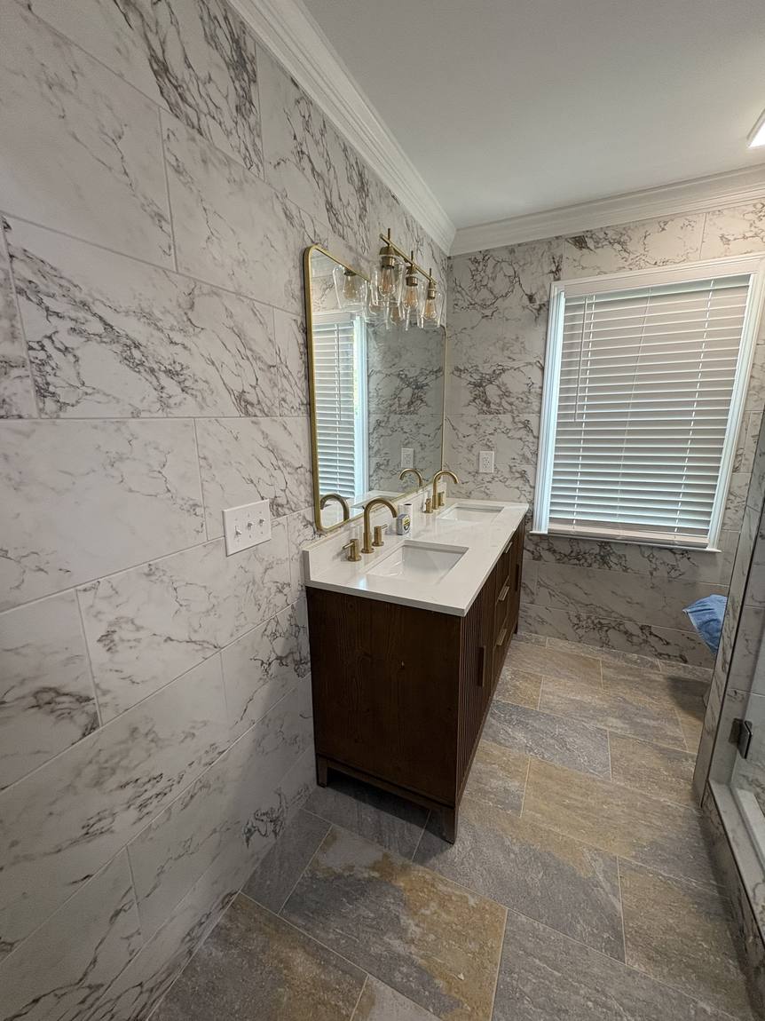 Double vanity with brass fixtures and marble-look tile